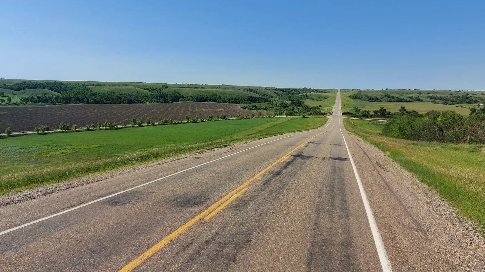 A two-lane rural Saskatchewan highway stretching over open prairie under a clear sky, a file photo not showing the scene of the incident.