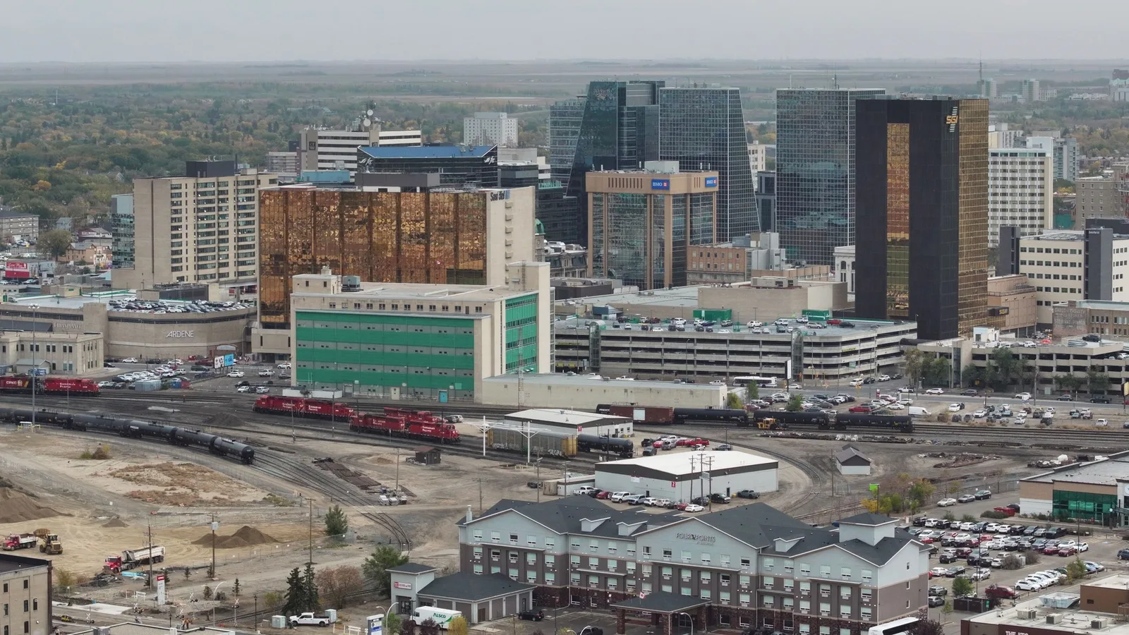 Elevated view of downtown Regina office buildings and rail yards under an overcast prairie sky.