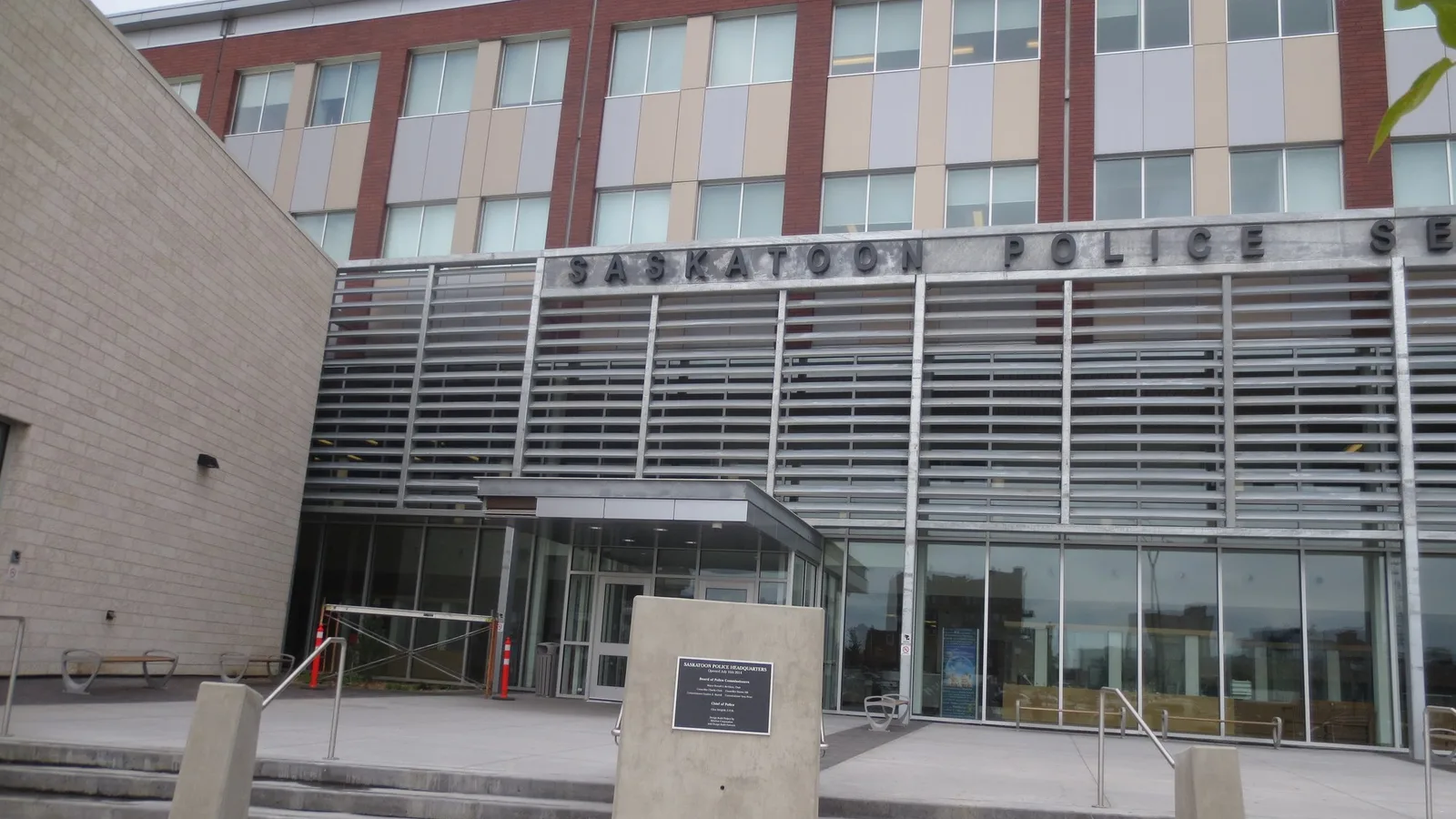 Modern multi-storey Saskatoon Police Service headquarters with large metallic lettering across the entrance facade.